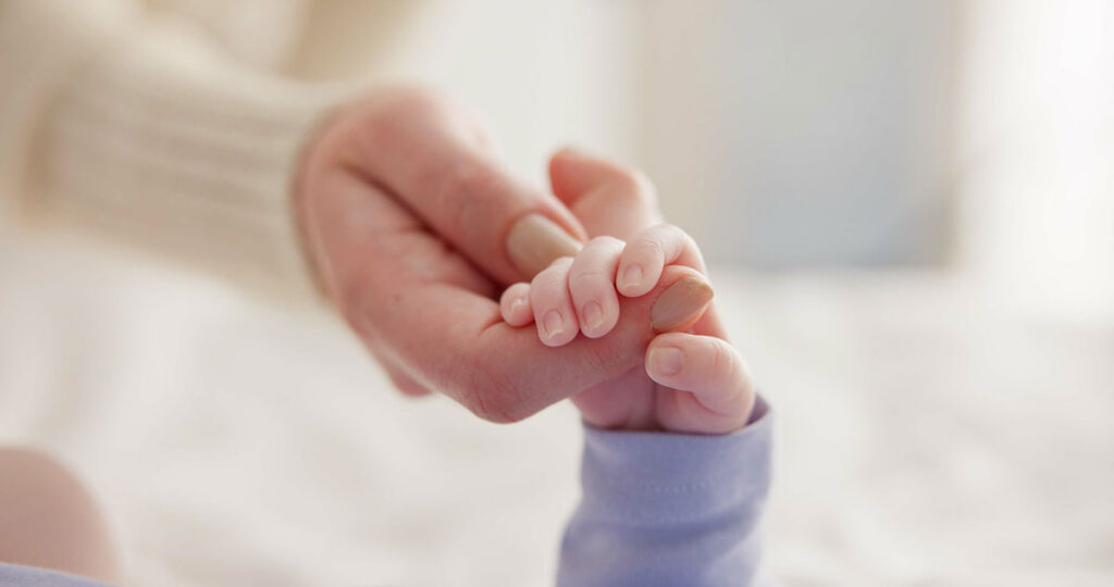 an adult and a baby holding hands