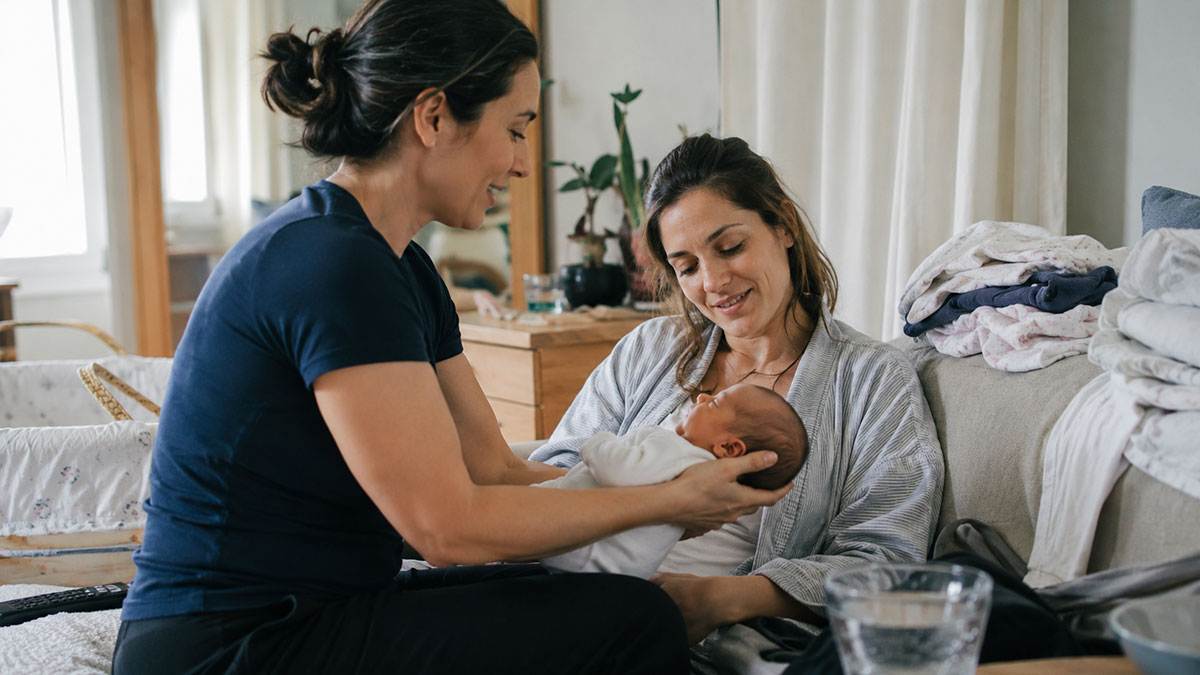 A postpartum care specialist supporting a mother and newborn baby at home